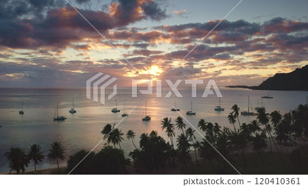 Sailboats yachts anchor in tropical island sea bay lagoon. Palm trees beach, vibrant clouds sunset sky. Remote wild nature paradise, exotic summer luxury travel tour. Natural background. Drone shot Sailboats yachts anchor in tropical island sea bay lagoon. Palm trees beach, vibrant clouds sunset sky. Remote wild nature paradise, exotic summer luxury travel tour. Natural background. Drone shot 120410361