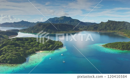 Turquoise water lagoon and green islands with sailboats yachts anchoring near motu in French Polynesia. Remote wild nature tropical paradise, exotic summer luxury travel. Drone aerial panorama shot Turquoise water lagoon and green islands with sailboats yachts anchoring near motu in French Polynesia. Remote wild nature tropical paradise, exotic summer luxury travel. Drone aerial panorama shot 120410384
