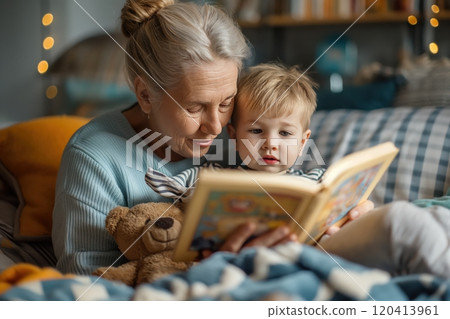 Grandmother reading a bedtime story to her little grandson along with a teddy bear 120413961