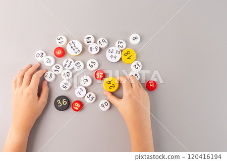 learn multiplication tables in interactive way for 3rd grade students, Child hand holding white bottle cap with math problems among scattered numbered caps on gray background, flat lay, learn multiplication tables in interactive way for 3rd grade students, Child hand holding white bottle cap with math problems among scattered numbered caps on gray background, flat lay, 120416194