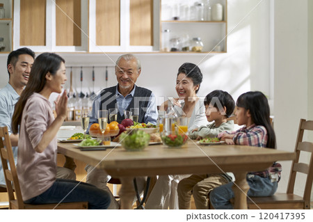 asian family chatting while eating meal 120417395