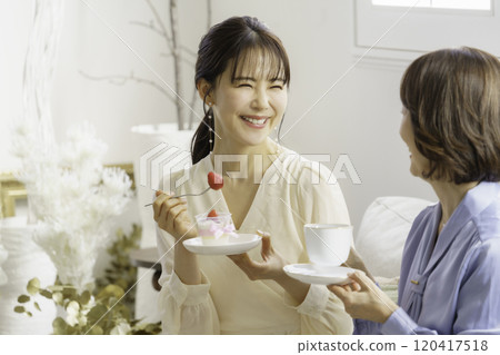 A mother and daughter in their 30s eating sweets at a cafe A mother and daughter in their 30s eating sweets at a cafe 120417518