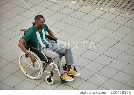 Minimal high angle view at adult African American man using wheelchair while moving in city outdoors on graphic pavement tiles copy space 120418566