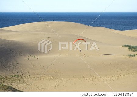 Summer in Tottori Prefecture: Paragliding over the Tottori Sand Dunes with Kujirajima in the background Summer in Tottori Prefecture: Paragliding over the Tottori Sand Dunes with Kujirajima in the background 120418854
