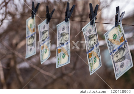 hundred-dollar bills hanging on a clothesline, secured with clothespins, symbolizing money laundering or financial dealings 120418903