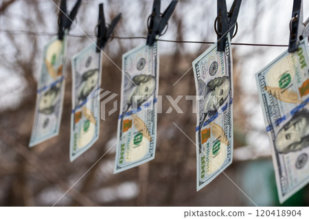 hundred-dollar bills hanging on a clothesline, secured with clothespins, symbolizing money laundering or financial dealings 120418904