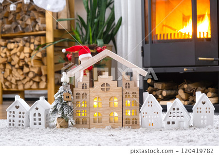 Key on Christmas tree and tiny house on cozy home with Christmas decor near the burning stove fireplace. Gift for New Year. Insurance, moving to new house, mortgage, rent and real estate Key on Christmas tree and tiny house on cozy home with Christmas decor near the burning stove fireplace. Gift for New Year. Insurance, moving to new house, mortgage, rent and real estate 120419782