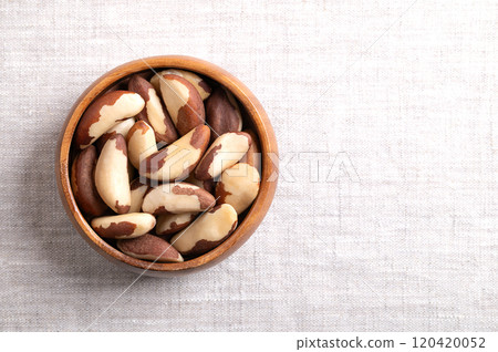 Brazil nuts in wooden bowl on linen fabric, with empty space for text. Shelled, dried seeds of Bertholletia excelsa. Notable for diverse content of micronutrients, especially high amount of selenium. 120420052