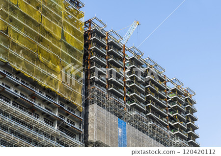 Low-angle view of cranes and steel structures of building construction with a blue sky background. 120420112