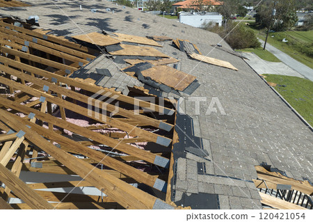 Wind damaged house roof with missing asphalt shingles after hurricane Ian in Florida. Repair of home rooftop concept 120421054