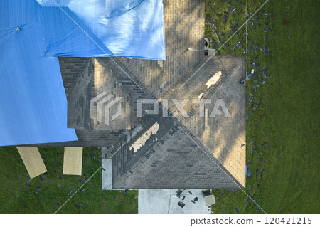 Top view of leaking house roof covered with protective tarp sheets against rain water leaks until replacement of asphalt shingles. Damage of building rooftop as aftermath of hurricane Ian in Florida 120421215