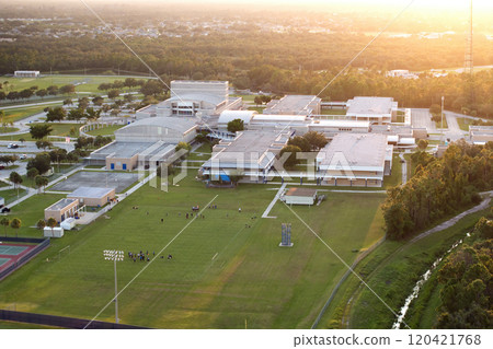 Public school in USA with school kids playing American football game on campus sports stadium at sunset. Physical exercise education in the United States Public school in USA with school kids playing American football game on campus sports stadium at sunset. Physical exercise education in the United States 120421768