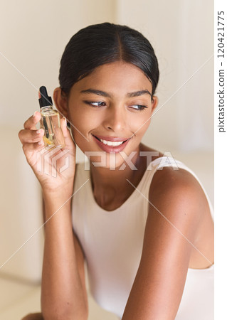 Woman Smiling While Holding Skincare Serum Bottle in Natural Light Setting Woman Smiling While Holding Skincare Serum Bottle in Natural Light Setting 120421775
