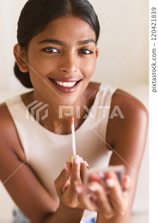Smiling Woman Applying Lip Gloss for a Natural Beauty Look 120421839