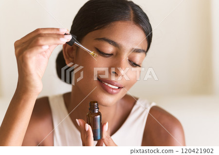 Woman Applying Facial Serum for Natural Glowing Skin in Bright Room 120421902
