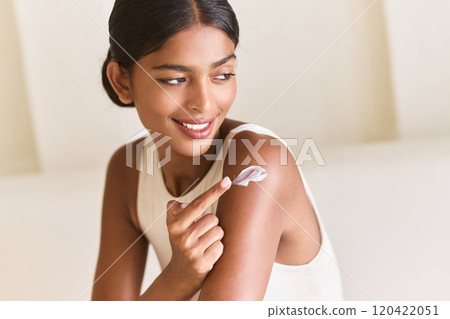 Woman Smiling While Applying Skincare Cream on Her Shoulder Indoors Woman Smiling While Applying Skincare Cream on Her Shoulder Indoors 120422051