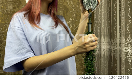 Girl attaches trunk of artificial Christmas tree to decorate her home. Installing fake spruce instead of pine trees for winter holidays to take care of nature Girl attaches trunk of artificial Christmas tree to decorate her home. Installing fake spruce instead of pine trees for winter holidays to take care of nature 120422456