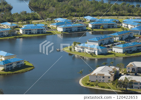 Hurricane damaged apartment buildings rooftops covered with protective plastic tarp against rain water leaking until replacement of asphalt shingles. Aftermath of natural disaster 120422653