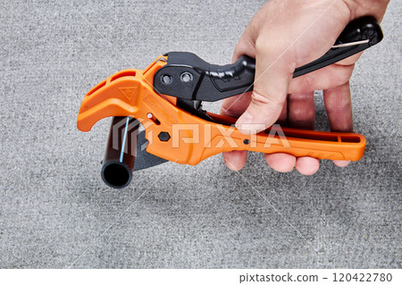 PVC pipe tubing cutter, one hand ratchet pipe cutting tool for plastic pipes, on gray background. PVC pipe tubing cutter, one hand ratchet pipe cutting tool for plastic pipes, on gray background. 120422780