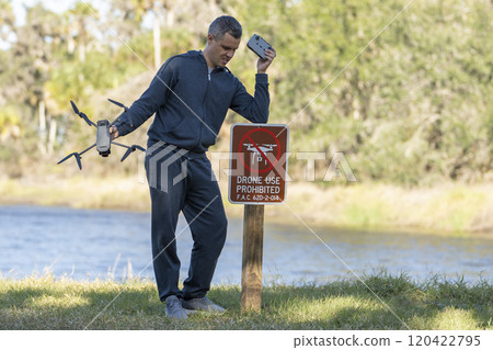 Drone operator is disappointed because he isn't allowed to fly his quadcopter in national park no drone area. Man is unable to use his UAV near restriction notice sign. Airspace use regulations 120422795