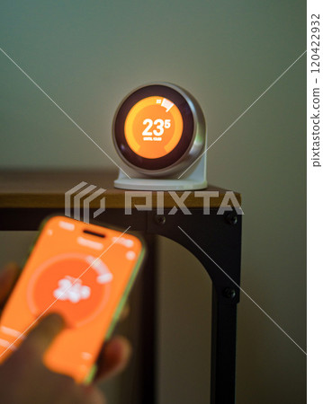 hand holding Smartphone Controlling Thermostat with Digital Temperature Display. High quality photo hand holding Smartphone Controlling Thermostat with Digital Temperature Display. High quality photo 120422932