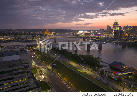Downtown district of Cincinnati city in Ohio, USA at night with driving cars traffic on bridge and brightly illuminated high skyscraper buildings. American travel destination Downtown district of Cincinnati city in Ohio, USA at night with driving cars traffic on bridge and brightly illuminated high skyscraper buildings. American travel destination 120423142