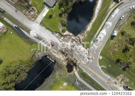 Destroyed bridge after hurricane flooding in Florida. Construction equipment at roadwork site. Reconstruction of damaged road after flood water washed away asphalt Destroyed bridge after hurricane flooding in Florida. Construction equipment at roadwork site. Reconstruction of damaged road after flood water washed away asphalt 120423162
