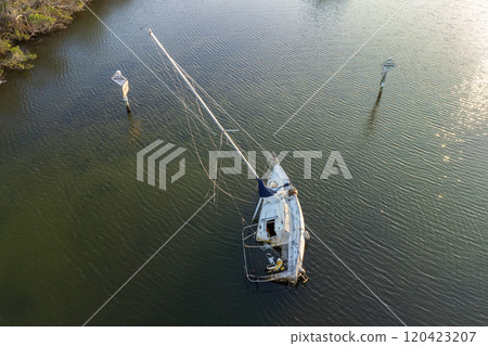 Capsized sunken sailing boat left forsaken on shallow bay waters after hurricane Ian in Manasota, Florida 120423207