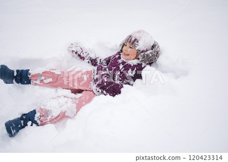 Little girl wearing a cozy winter outfit, happily exploring deep snow. The pure white snow surrounds her, creating a dreamy winter scene full of childhood wonder 120423314