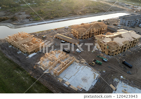 Aerial view of unfinished wooden frames of apartment buildings under construction. Development of residential housing in American suburbs. Real estate market in the USA 120423943