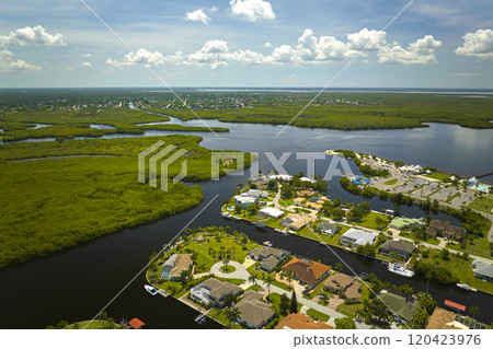 Aerial view of residential suburbs with private homes located near wildlife wetlands with green vegetation on sea shore. Living close to nature concept Aerial view of residential suburbs with private homes located near wildlife wetlands with green vegetation on sea shore. Living close to nature concept 120423976