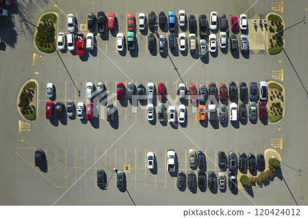 Aerial view of many colorful cars parked on parking lot with lines and markings for parking places and directions. Place for vehicles in front of a strip mall plaza Aerial view of many colorful cars parked on parking lot with lines and markings for parking places and directions. Place for vehicles in front of a strip mall plaza 120424012