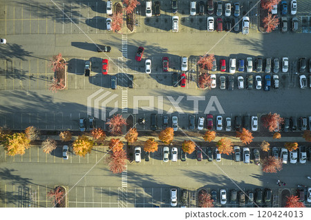 Aerial view of many colorful cars parked on parking lot with lines and markings for parking places and directions. Place for vehicles in front of a strip mall plaza Aerial view of many colorful cars parked on parking lot with lines and markings for parking places and directions. Place for vehicles in front of a strip mall plaza 120424013