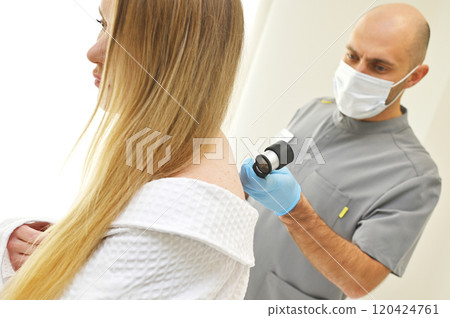 A dermatologist examines neoplasms on the patient's skin using a special dermatoscope device. Prevention of melanoma. A dermatologist examines neoplasms on the patient's skin using a special dermatoscope device. Prevention of melanoma. 120424761