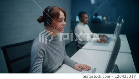 Call center office: Female technical support specialist in headset monitoring data on PC 120425317