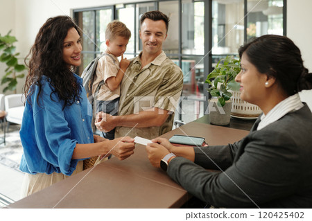 Family Checking into Hotel Reception with Smiling Faces 120425402