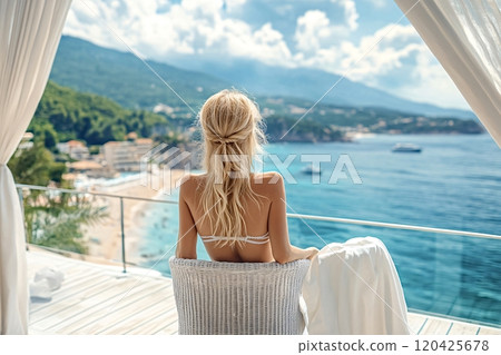 Woman relaxing on balcony overlooking tropical beach and ocean 120425678