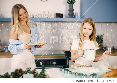 Family preparation of ginger biscuits with daughter. Mother and little girl cooking cookies. Blonde woman wearing blue shirt and girl white t-shirt. Family preparation of ginger biscuits with daughter. Mother and little girl cooking cookies. Blonde woman wearing blue shirt and girl white t-shirt. 120425792