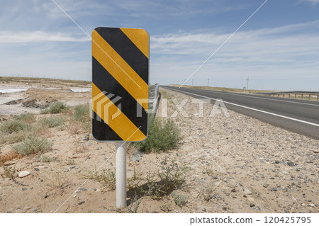 Road sign with yellow and black stripes on the roadside, warning sign 120425795