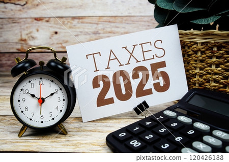 Taxes 2025 text with alarm clock and calculator on wooden background 120426188