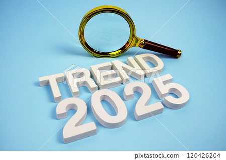 Trend 2025 word with magnifying glass top view on blue background 120426204