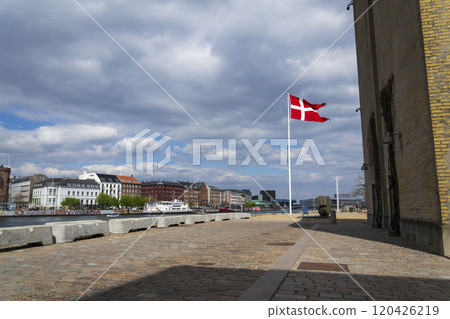 A waving Danish flag on a pole on the waterfront in the center opposite the famous Nyhavn A waving Danish flag on a pole on the waterfront in the center opposite the famous Nyhavn 120426219