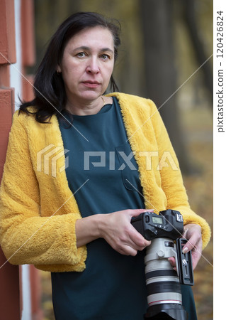 Elderly woman in bright clothes with a camera in her hands. 120426824