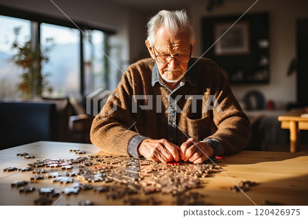 An elderly man is putting together puzzles. 120426975