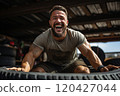 Smiling man in sportswear lifting large car tires in the gym. 120427044