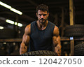 Smiling man in sportswear lifting large car tires in the gym. 120427050