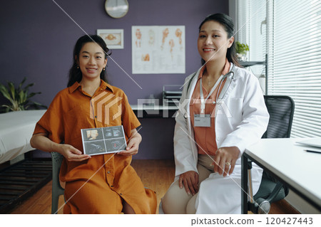 Smiling Pregnant Woman with Doctor Holding Ultrasound 120427443