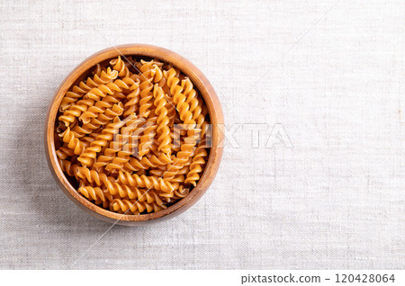 Chickpea spiral pasta in a wooden bowl, with empty space for text. Small fusilli, a pasta variety with helical or corkscrew shape, made of gluten free chickpea flour, an alternative to wheat flour. Chickpea spiral pasta in a wooden bowl, with empty space for text. Small fusilli, a pasta variety with helical or corkscrew shape, made of gluten free chickpea flour, an alternative to wheat flour. 120428064
