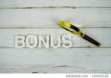 Bonus alphabet letters and magnifying glass top view on wooden background 120428189