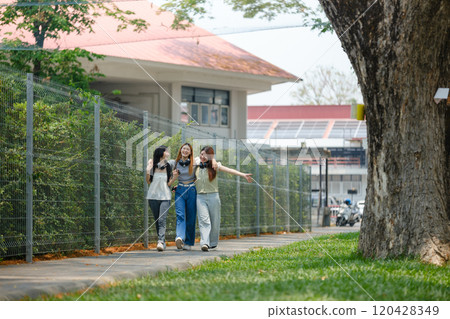 Three women walking down a sidewalk in front of a building 120428349